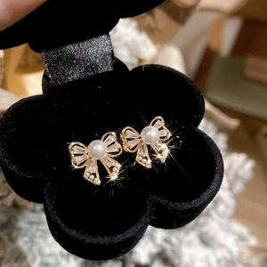 Detailed view of bow earrings with pearls and crystals in a black velvet box