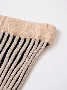 Macro shot of striped knit leg warmers showing soft beige and black texture and ribbed cuffs