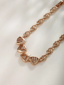 Close-up of geometric triangle charms with pavé cubic zirconia on a gold chain