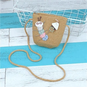 Detailed macro of a khaki straw bag for kids with colorful caterpillar and mushroom patches
