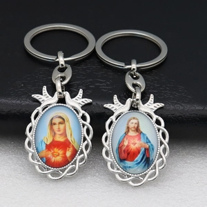 Close-up of silver metal religious keychains featuring Virgin Mary and Sacred Heart