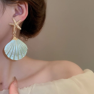 Detail of starfish and turquoise pearl shell earring set on model for beach vacations