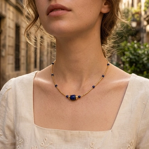 Close-up of lapis lazuli beaded necklace with gold chain worn by a female model