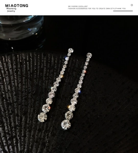 Macro shot of silver rhinestone tassel earrings with gradient crystal drops on dark texture