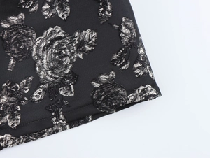Close-up of black fabric with silver rose jacquard floral pattern on dress