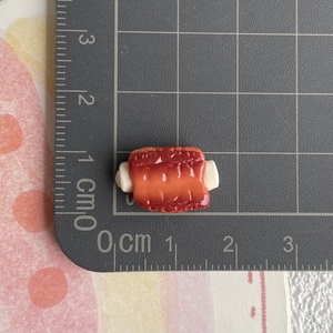 Detaillierte Makroansicht zur Größenmessung eines Miniatur-Steak-Modells aus Harz auf einem Lineal