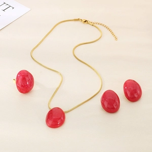 Detail view of red enamel oval pendant necklace earrings and ring set in gold-tone finish