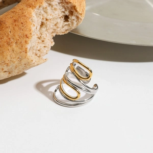Artistic two-tone gold and silver stainless steel ring with twisted lines on warm background