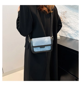 Detail of denim blue and black leather patchwork crossbody bag with slim strap