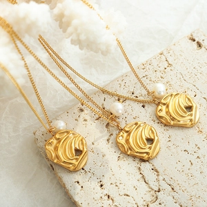 Irregular lava gold pendant necklace with freshwater pearls on stone background