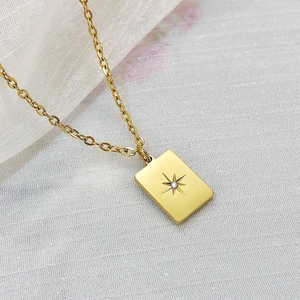 Detail of gold rectangular pendant with starburst engraving and sparkling crystal inlay