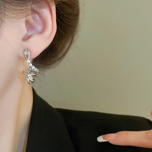 Close-up of a silver snake-shaped earring with white crystals on a model's ear