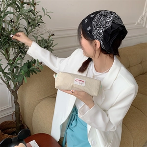 Cream colored fabric pencil case with natural texture held by a person in a cozy room