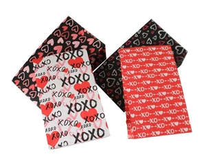 Makroaufnahme von Valentinstag-Geschenktüten mit XOXO- und Herzmustern in Rot und Schwarz