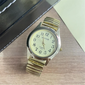 Detail of quartz watch with stretch band and clear Arabic numerals on a wooden surface