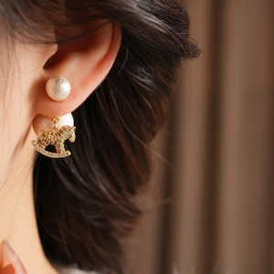 Macro view of crystal rocking horse earring with texture pearl detail on model
