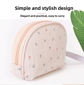 Detail of beige canvas makeup bag featuring navy blue anchor prints and a hand strap