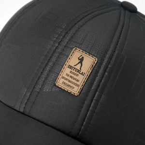 Macro shot of texture on black winter baseball cap with stitched leather logo patch
