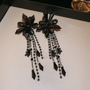 Macro detail of black crystal flower earrings with long layered metal tassel chains