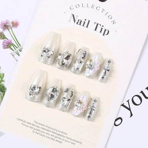 Detailed view of luxury press-on nails with large rhinestones, pearls and silver glitter