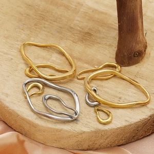 Irregular gold and silver stainless steel oval pendants displayed on a wooden tray