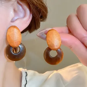 Minimalist resin and wood geometric drop earrings with earthy tones shown on a model