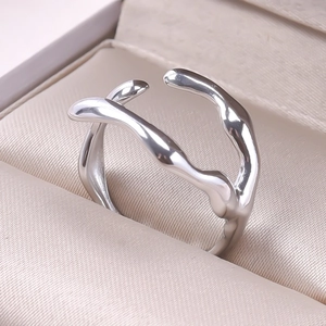 Macro shot of silver irregular wave double-line open ring on beige silk background