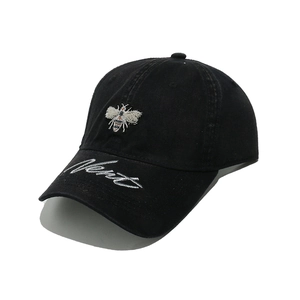 Close-up of colorful bee embroidery and white script text on black cotton baseball cap