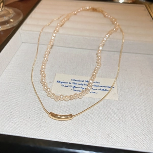 Détail d'un collier double rang avec perles et chaîne serpent dorée dans un écrin