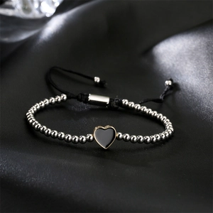 Detail of adjustable braided bracelet with silver beads and black enamel heart charm