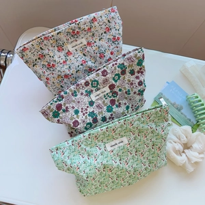 Three-piece set of floral cotton makeup bags with simple wish label on off-white surface