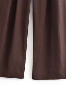 Dettaglio dei pantaloni vintage marroni che mostra l'orlo e la trama del tessuto a navetta