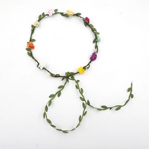 Detail of colorful fabric roses and green leaves on a bohemian floral crown headband