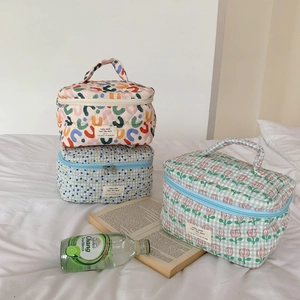 Détail des trousses à maquillage en coton matelassé avec motifs floraux et fermeture éclair