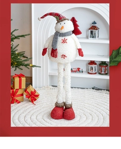 Detail of plush Christmas snowman figurine with long legs near a cozy white fireplace