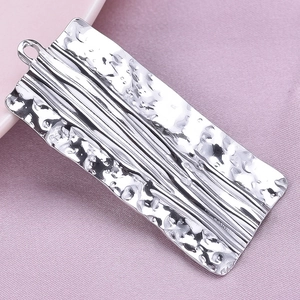 Detailed macro view of silver hammered metal rectangular pendant with parallel line textures