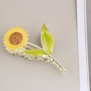 Vue détaillée d'une pince à cheveux tournesol jaune en métal avec émail coloré et strass