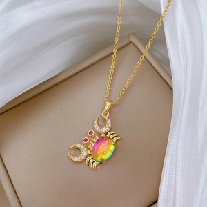 Golden crab necklace with colorful crystal pendant and white rhinestones on jewelry box