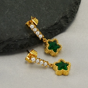 Boucles d'oreilles étoiles avec cristaux verts et perles sur un fond en pierre naturelle