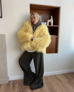 Detail of yellow faux fur oversized coat paired with olive green wide-leg trousers