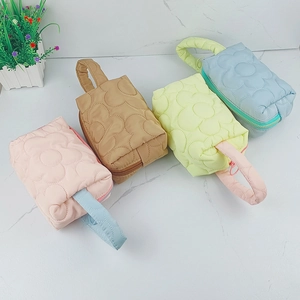 Flat lay of quilted cosmetic bags in pink, brown, yellow and blue on marble background