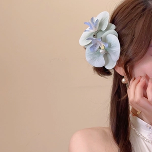 Detailed side view of fabric orchid hair clip with pearls on a model