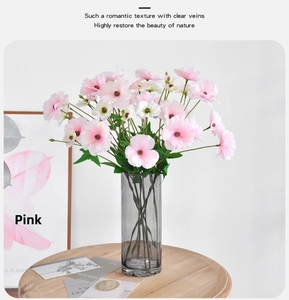 Pink faux ranunculus and lisianthus flowers in a grey glass vase on a wooden table