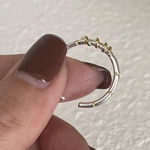 Detail of adjustable 925 silver ring featuring a two-tone silver and gold finish design