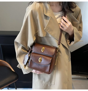 Detail of vintage brown leather crossbody bag with double gold twist locks and hangtag