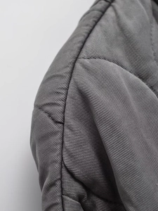 Close-up of the grey quilted diagonal twill fabric texture on a casual winter jacket