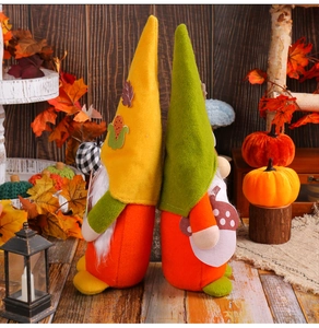 Close-up of autumn harvest gnomes with felt hats and maple leaves on wooden floor