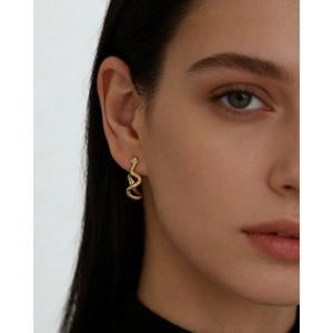Elegant gold snake hoop earrings with detailed scale texture worn by a model