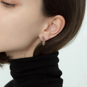 Polished silver titanium hoop earring detail on a model with a minimalist chic style