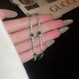 Détail de pierres précieuses vert émeraude et zircons blancs sur bracelets dorés et argentés